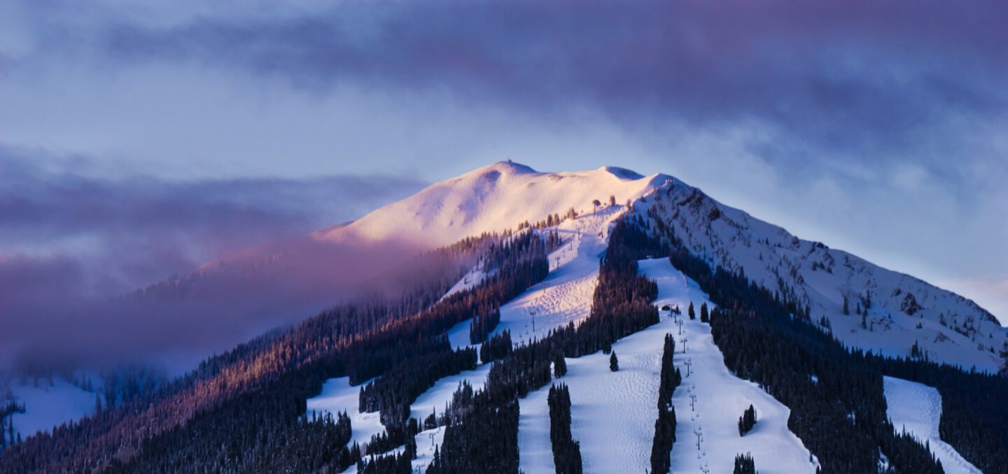 A snow-covered mountain under low pink light.