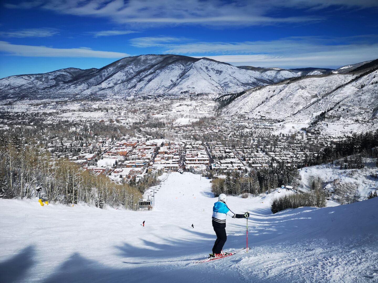 Aspen in winter, seen across a snowy slope with mountains beyond.